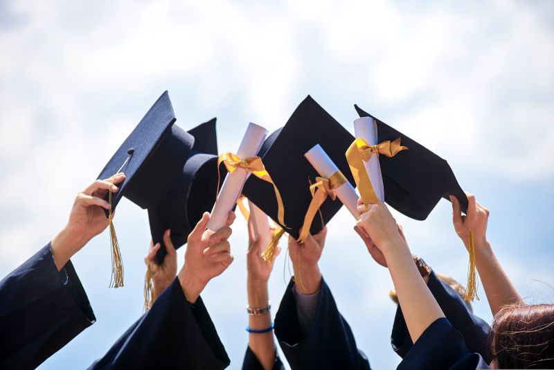 Un groupe d'étudiants tout juste diplômés, levant leur chapeau et diplôme dans les airs