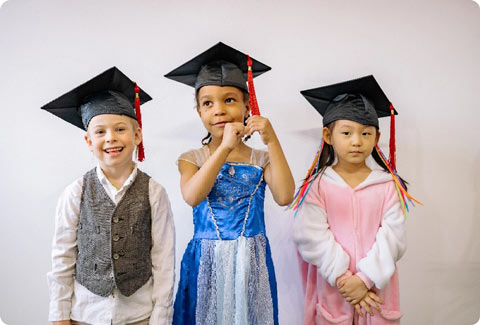 trois jeunes enfants portant des chapeaux de diplômés